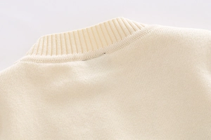 Detailed close-up of ribbed crew neck on soft cream-colored knitted kids sweater