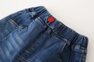 Detail of boys denim jeans showing elastic waistband and red button with JEANS text