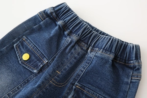 Détail d'un jean enfant bleu foncé avec taille élastique et poche à bouton jaune