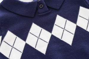 Detail of navy blue kids knit polo sweater featuring white argyle pattern and soft texture