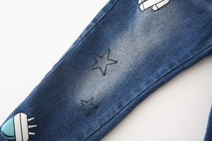 Detail of boys denim jeans showing vintage wash texture and cartoon spaceship print
