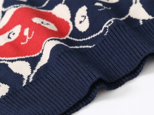 Detailansicht eines dunkelblauen Strickpullovers mit Cartoon-Jacquard und Rippstricksaum