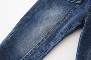 Détail du tissu denim bleu avec effet de délavage vintage et surpiqûres jaunes contrastées