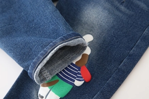 Detailed close-up of dark blue washed denim fabric with colorful cartoon dog print