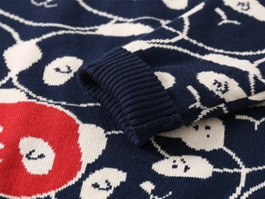 Detailaufnahme eines dunkelblauen Strickpullovers mit weißem Muster und Rippbündchen