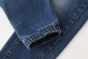 Détail des poignets élastiques sur un pantalon en jean délavé bleu foncé pour enfants