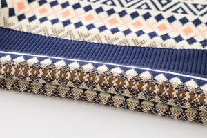 Detail of chunky knit sweater with geometric diamond jacquard and ribbed cuff texture