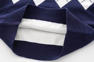 Close-up of classic blue and white argyle pattern knit cardigan with ribbed cuff detail
