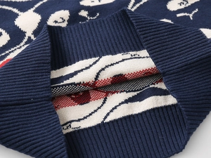 Detail eines dunkelblauen Strickpullovers mit Rippbündchen und Jacquard-Cartoon-Muster