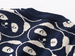 Detailansicht des Rippstrickbündchens und Panda-Jacquards auf einem marineblauen Pullover