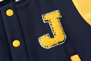 Close-up of boys' baseball jacket featuring yellow chenille letter J patch and snap buttons