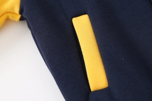 Detail of yellow welt pocket and navy knit fabric on boys' baseball jacket
