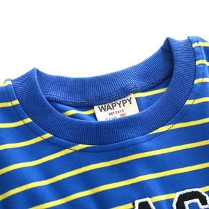 Detail of round neckline with blue ribbing and brand label on yellow striped kids' shirt