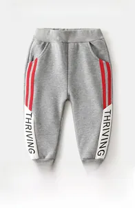Detail of fleece-lined grey kids jogger pants with THRIVING lettering and red stripes