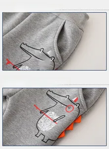 Detail view of children's fleece joggers with cartoon crocodile print and 3D dinosaur spikes