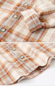 Détail de la texture du tissu à carreaux et des boutons en résine d'une chemise enfant