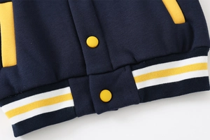Detailed close-up of navy baseball jacket with yellow buttons and striped ribbed hem
