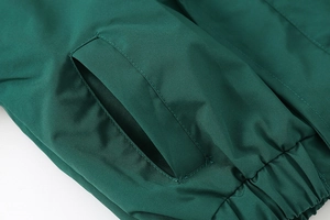 Detail of dark green outdoor jacket featuring reinforced pockets and elastic hem