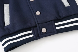 Detail of navy blue kids jacket showing matte buttons and striped ribbed hem texture