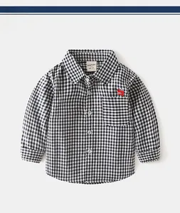 Detail of baby boys plaid shirt featuring a cute red dinosaur embroidery on the pocket