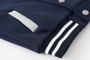 Detail of navy blue kids jacket showing ribbed hem with white stripes and matte buttons