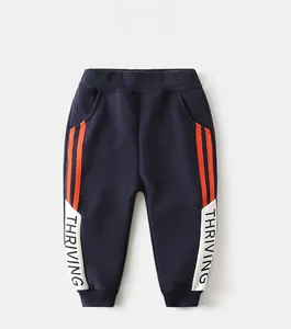 Detail of navy blue kids fleece joggers featuring orange side stripes and THRIVING print