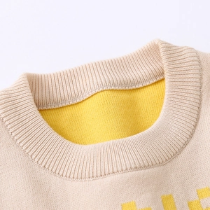 Close-up of a double-layered ribbed crewneck on a beige and yellow knit sweater