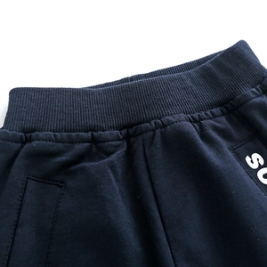 Detail of navy blue kids' cotton sweatpants featuring ribbed elastic waistband and SO print
