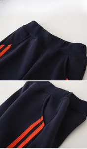 Detail of kids navy fleece joggers showing elastic waistband and orange side stripes