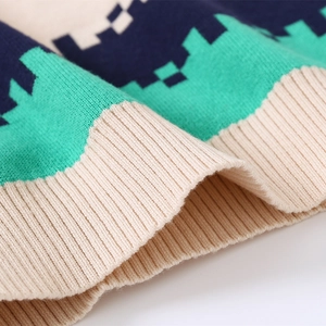 Macro view of boy's knit sweater ribbed hem with geometric block patterns in navy and green