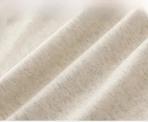 Gros plan sur un tissu en maille chiné gris clair montrant sa texture et sa douceur