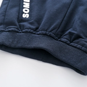 Detail of navy knit sweatshirt showing elastic ribbed hem and SOME letter print