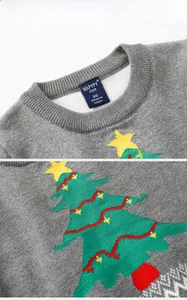 Detail of soft knit children grey sweater featuring green Christmas tree pattern and neck label