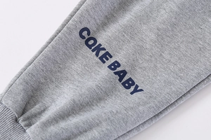 Détail du pantalon de sport gris avec imprimé bleu CAKE BABY et bords côtelés