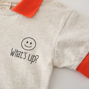 Polo enfant gris chiné avec col orange et motif graphique visage souriant noir