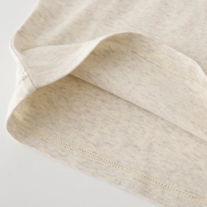 Gros plan détaillé sur les coutures doubles d'un ourlet en maille beige pour enfant