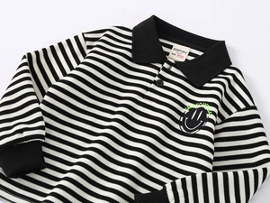 Detailed view of striped kids polo shirt featuring ribbed collar and smiling face patch