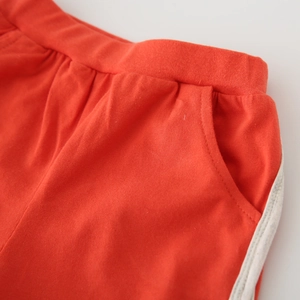 Détail du short orange pour enfant avec taille élastique et rayures blanches latérales