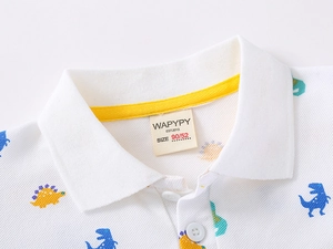 Detail of cotton pique fabric with colorful dinosaur prints and polo neck label
