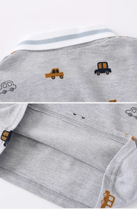 Détail du polo gris pour enfant montrant le tissu respirant et les imprimés autos