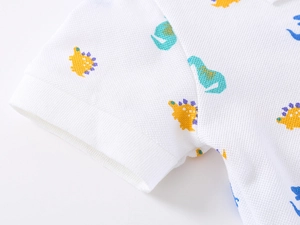 Close-up of white pique cotton polo shirt featuring colorful cartoon dinosaur prints