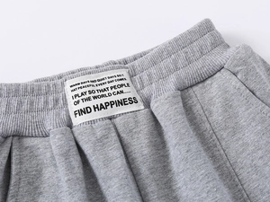 Detail of the elastic ribbed waistband with white fabric patch on gray kids joggers