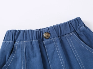 Detail of blue cotton shorts featuring an elastic waistband and brown decorative button