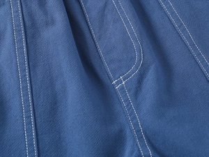 Detailed macro view of dark blue boys' shorts featuring white double-row contrast stitching