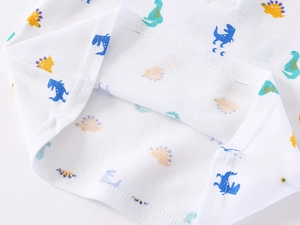 Close-up of boys' white cotton piqué polo shirt showing fine stitching and dinosaur print