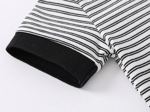 Détail de la manche d'un polo rayé noir et blanc avec texture en maille piquée