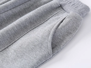 Detail of children's grey joggers showing elastic waistband and knit cotton texture
