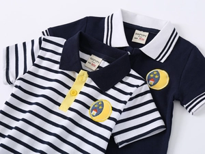 Dettaglio di due polo in cotone per bambini con strisce e ricami di luna e stelle