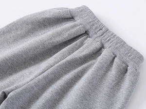 Detail of gray knitted kids joggers featuring an elastic waistband and soft cotton fabric
