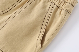 Detailed macro view of khaki cotton shorts featuring elastic waist and brown contrast stitching